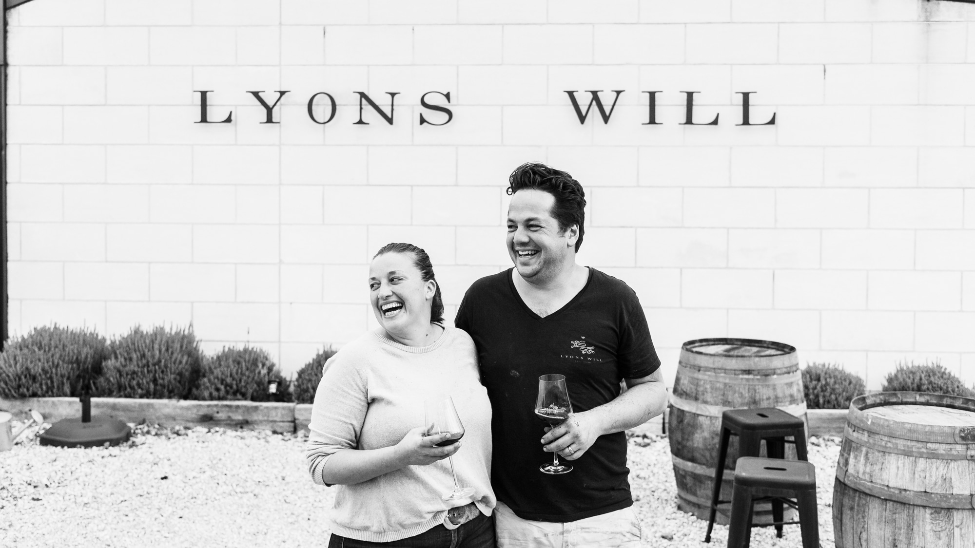Black and white photo of man and woman outside with barrels 